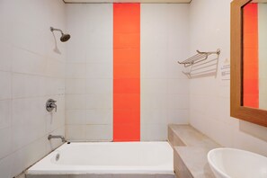 A bathroom with a white bathtub, a shower, and a sink. - Collection O Bali near Sanur Beach formerly Akarsa Kokoro (Denpasar)