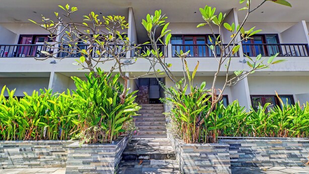 A multi-story building with a staircase leading to the entrance, surrounded by lush greenery and stone steps. - Collection O Bali near Sanur Beach formerly Akarsa Kokoro (Denpasar)