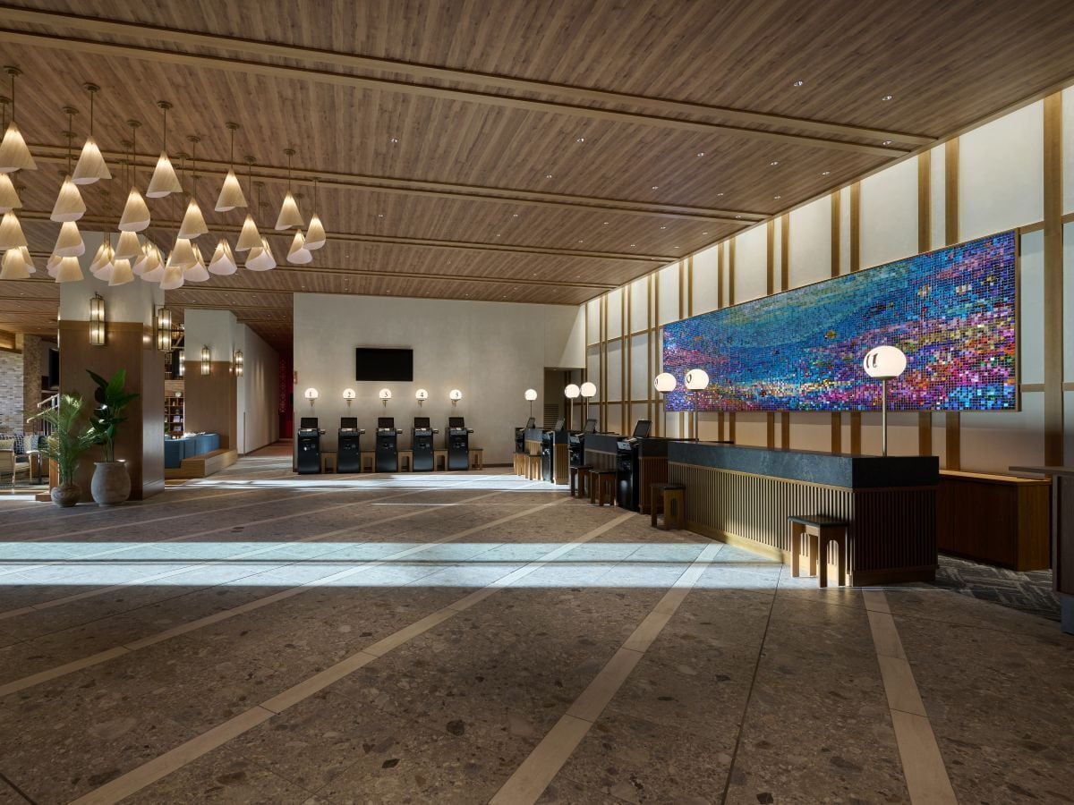 A spacious lobby with a reception desk, seating area, and a large wall art piece.