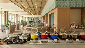 A buffet setup with various food containers and utensils, a ceiling with a grid pattern, and a tiled wall with a repeating design. - The Royal Park Hotel Maihama Resort Tokyo Bay (Urayasu)