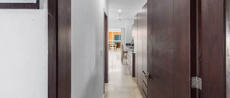 A hallway with a number sign, wooden doors, and a view into a room with a dining area.