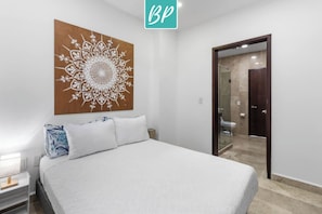 A bedroom with a large bed, a wall-mounted artwork, and a bathroom visible through an open door.