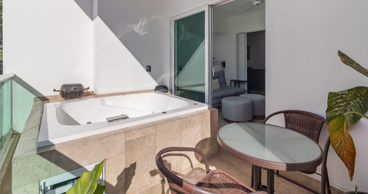 Un baño moderno con una bañera grande, cabina de ducha de vidrio y una zona de estar con mesa y sillas.