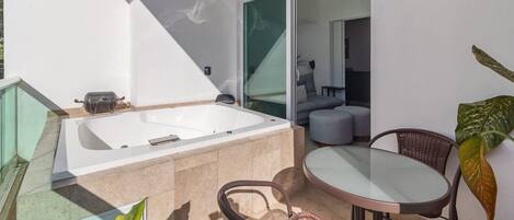 Un baño moderno con una bañera grande, cabina de ducha de vidrio y una zona de estar con mesa y sillas.