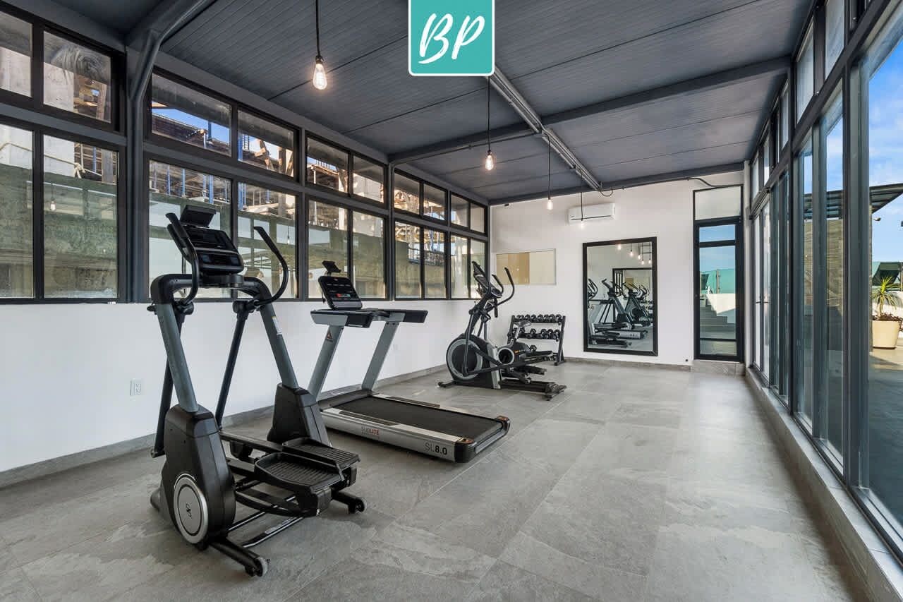 A gym with treadmills, stationary bikes, and dumbbells.