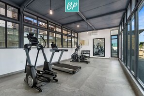A gym with treadmills, stationary bikes, and dumbbells.