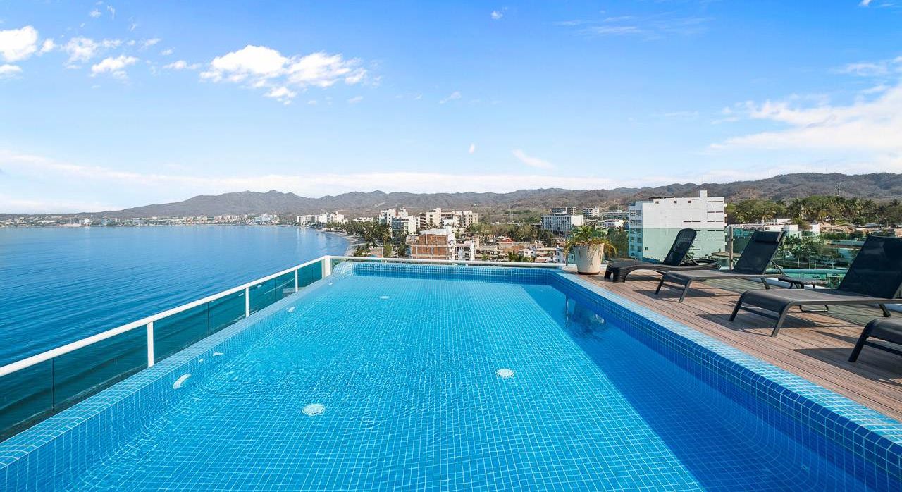 A swimming pool with a view of the sea and buildings in the background.