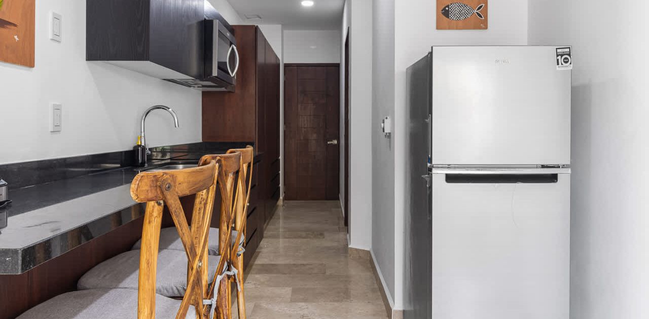 Une cuisine équipée d’un réfrigérateur, d’un four à micro-ondes et d’une chaise en bois.