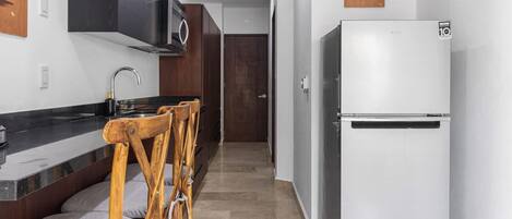 Une cuisine équipée d’un réfrigérateur, d’un four à micro-ondes et d’une chaise en bois.