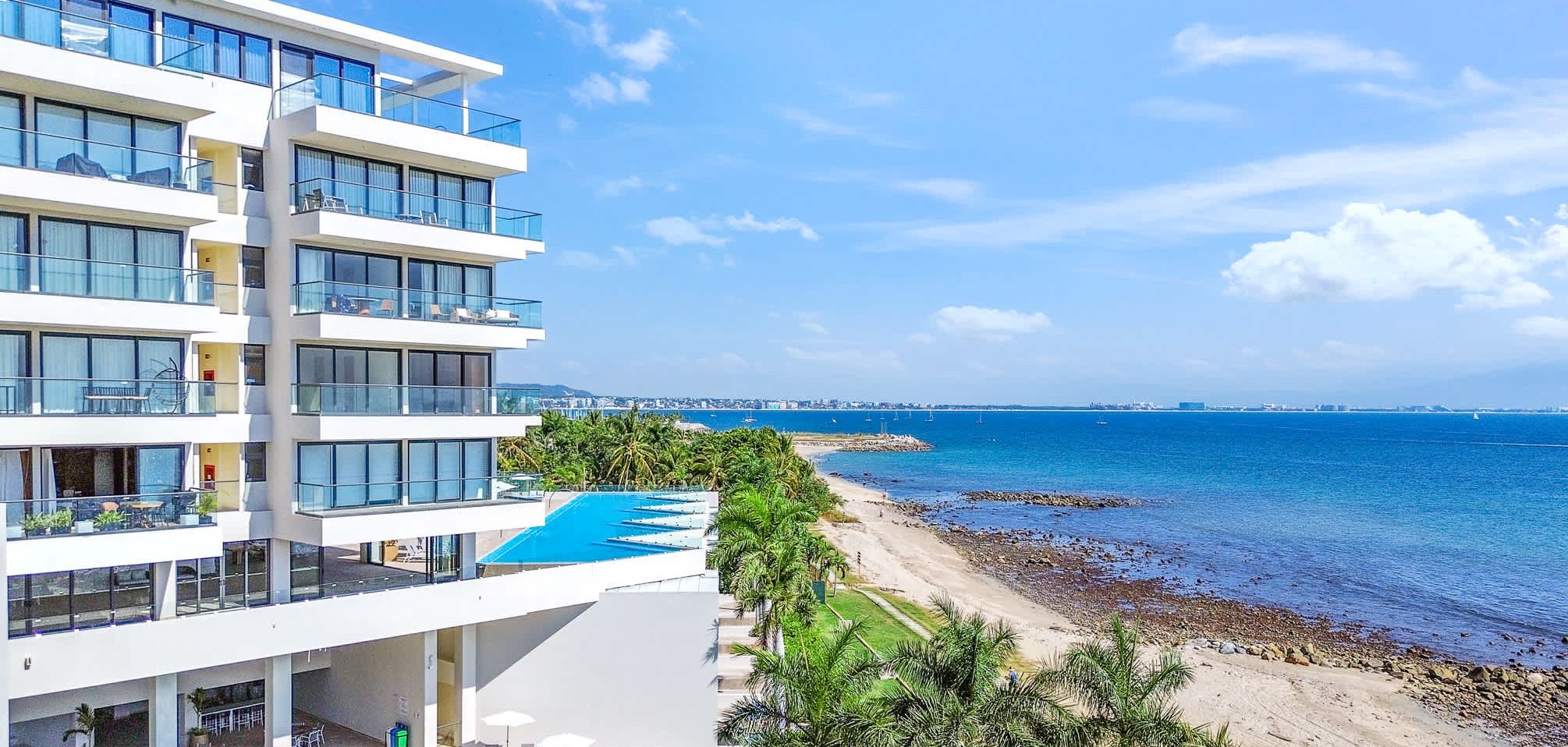 A multi-story hotel with a pool, beach access, and ocean views.