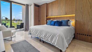 A modern bedroom with a large bed, wooden headboard, and a balcony with a view.