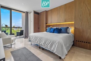 A modern bedroom with a large bed, wooden headboard, and a balcony with a view.