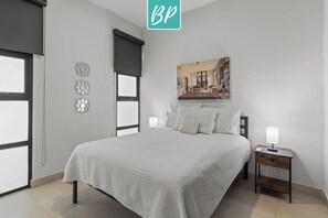 A bedroom with a large bed, a nightstand, a wall-mounted painting, and decorative wall art. - 2BR, Rooftop Pool w/ Views, & Parking: Vista 101 (Bucerías)