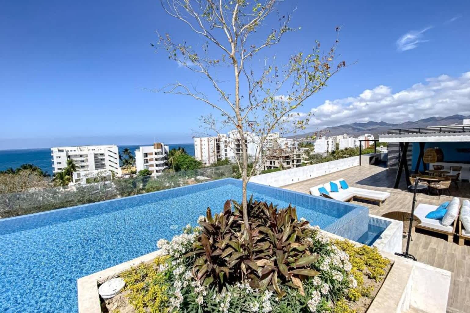 Una piscina en la azotea con vistas despejadas al océano y edificios circundantes.