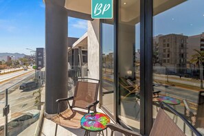 A hotel balcony with a BP sign, a glass railing, and a view of a busy street and buildings.