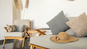 A modern living room with a grey sofa, patterned cushions, a woven basket, and a straw hat on the floor. - LaLeBay Seminyak (Seminyak)