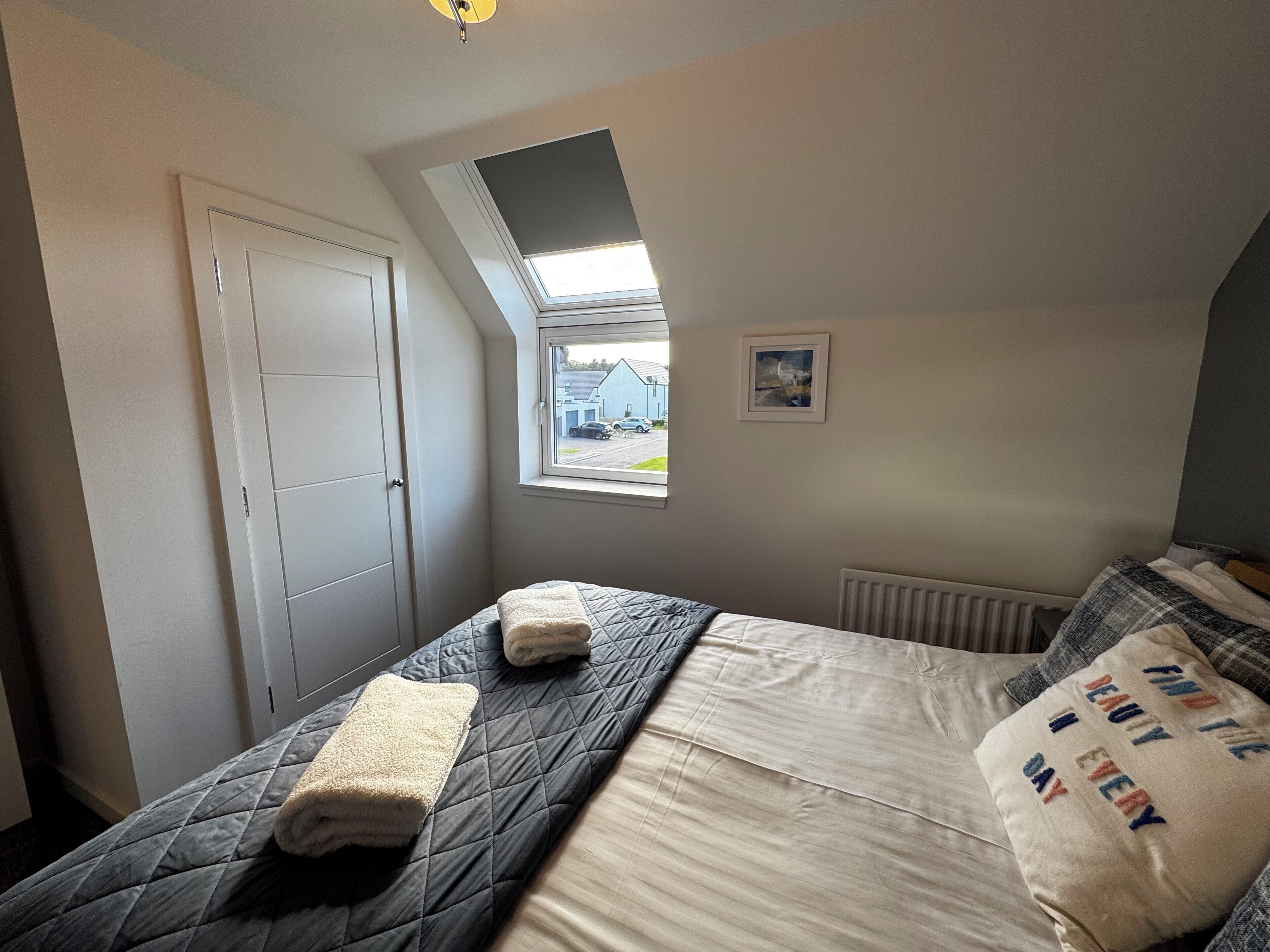 A bedroom with a bed, a window, a radiator, and a door.