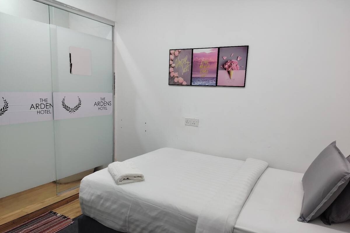 A hotel room with a bed, a small rug, and a wall with three framed pictures.