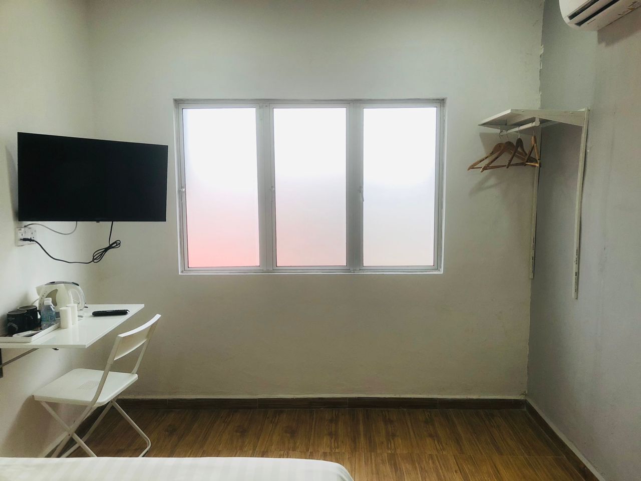 A small, sparsely furnished room with a single window, a desk, and a chair.