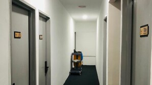 A hallway with doors labeled 106 and 111, a cart with items, and a ceiling light. - The Ardens Hotel - Pekan Nenas (Pekan Nanas)