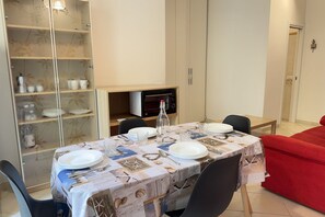 A dining area with a table set for four, a microwave, and a cabinet with dishes.