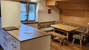 Een gezellige keuken met een houten plafond, een eethoek met een bank, en een raam met uitzicht.