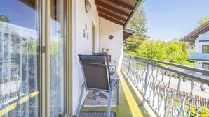 En balkon med træloft, en stol, et lille bord og udsigt over det omkringliggende område.