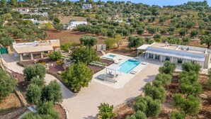 Eine Luftaufnahme eines Wohngebiets mit Pool, überdachter Terrasse und einem weißen Gebäude mit flachem Dach.