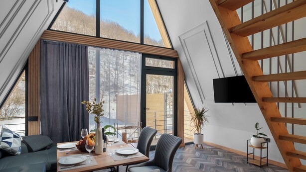 A dining area with a table set for two, a sofa, and a view of the outdoors. - Ari Home Aghveran (Agveran)