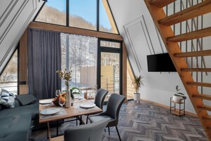 Un comedor con una mesa preparada para dos personas, un sofá y vistas al exterior.