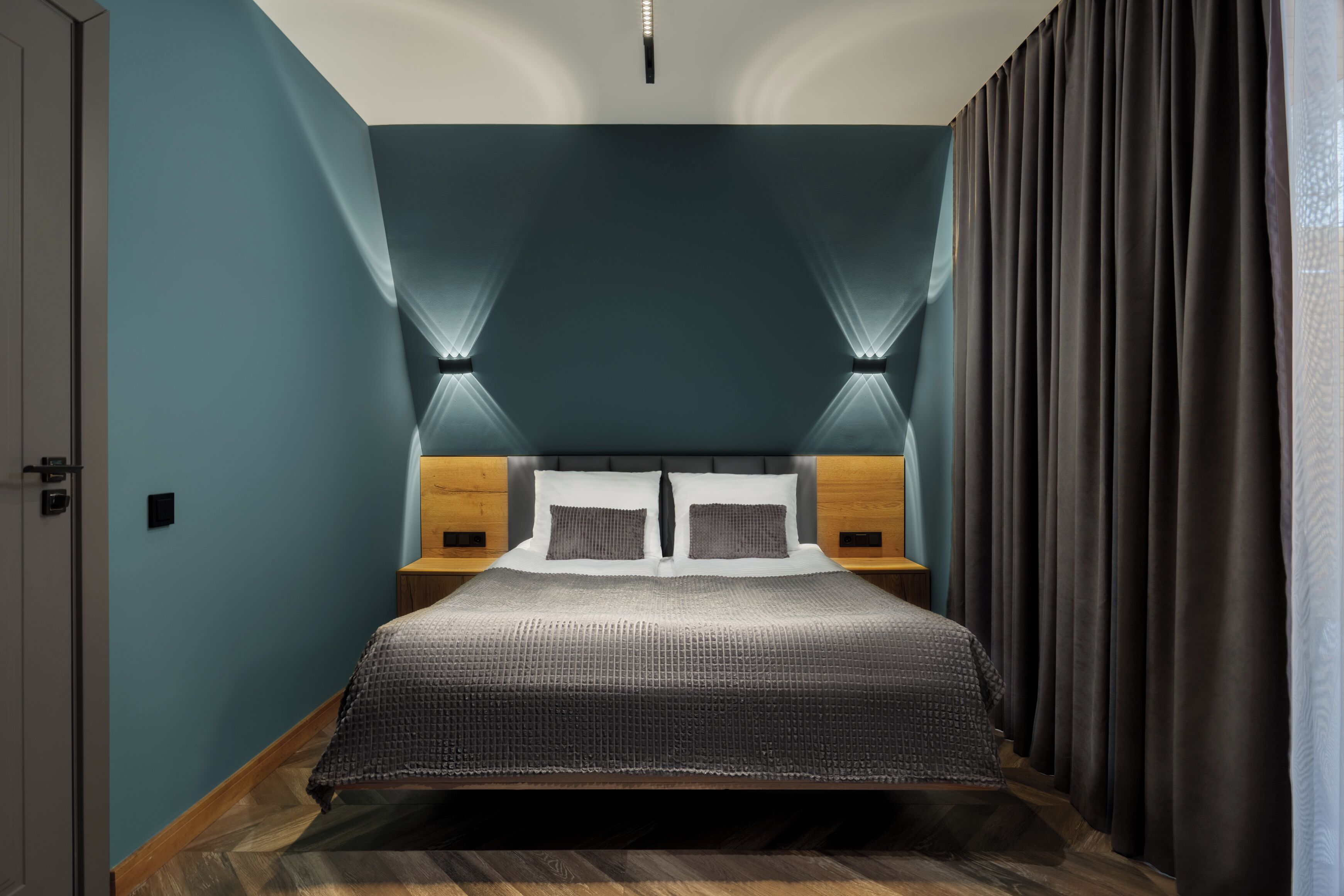 A modern bedroom with a large bed, wooden headboard, and two bedside tables.