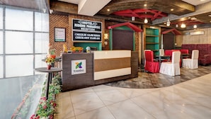 A hotel reception area with a check-in counter, a reception desk, and a seating area with red chairs. - Treebo Masterprice Inn - 15 Mins From Airport (Lucknow)