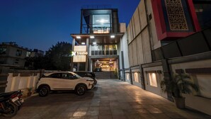 A modern building with a glass facade, a staircase leading to the entrance, and a white car parked in front. - Treebo Masterprice Inn - 15 Mins From Airport (Lucknow)