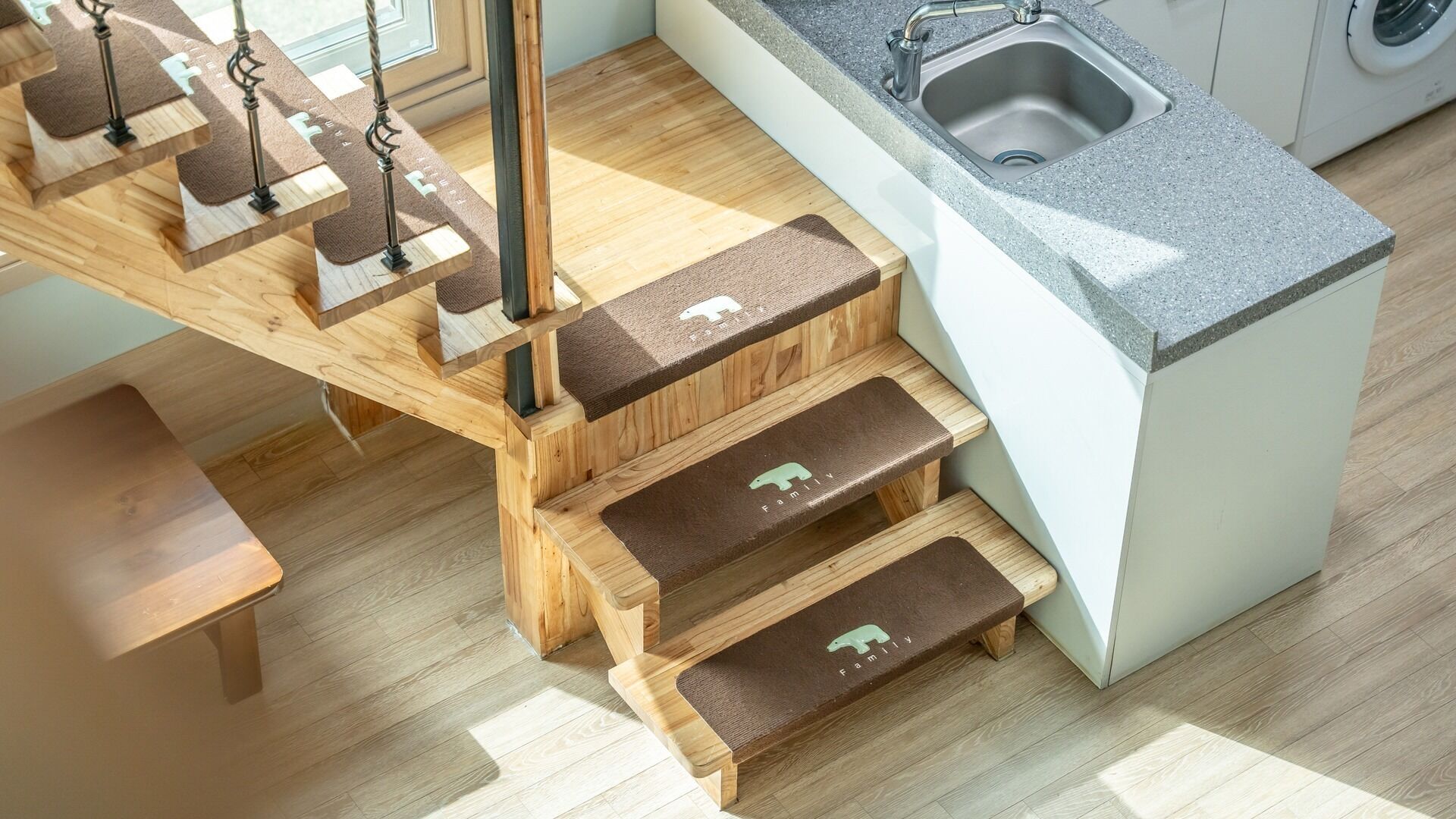 Cocina con encimera de granito, pileta de acero inoxidable y escalera de madera con el logotipo de un oso.