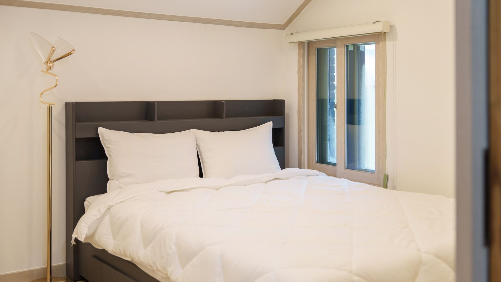 A bedroom with a bed, a nightstand, and a window.
