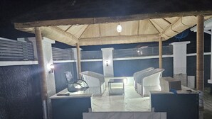 A covered outdoor seating area with a table and chairs, steps leading up to it, and a light fixture above. - Bimsy's Place  (Abuja)