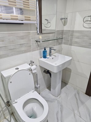 Bathroom features a pedestal sink, toilet, and glass shower enclosure.