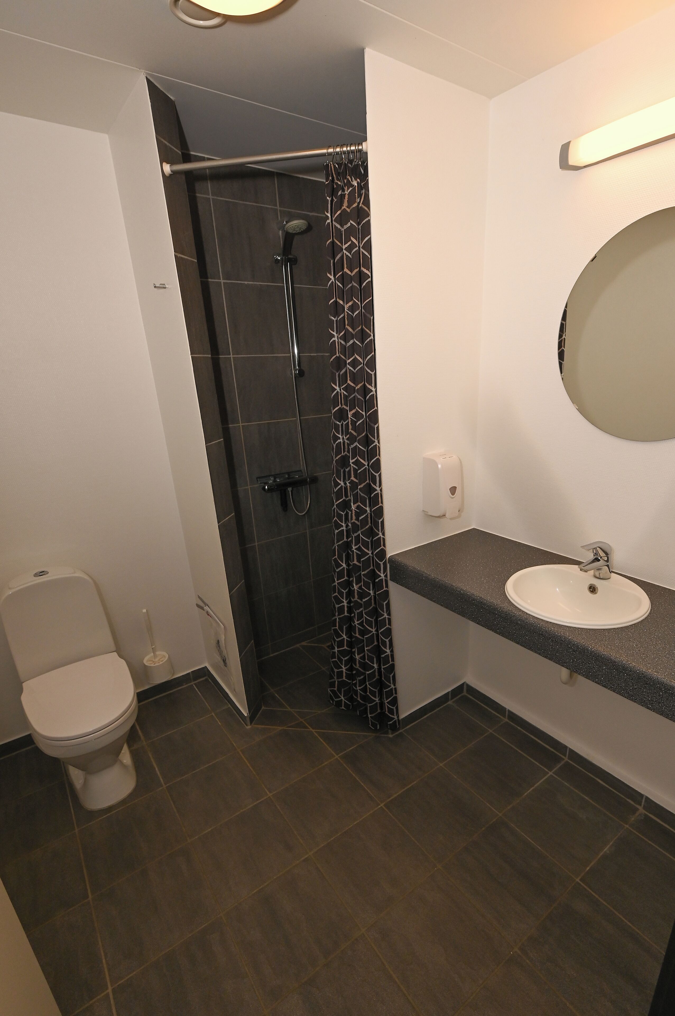 A modern bathroom with a shower, toilet, and sink.