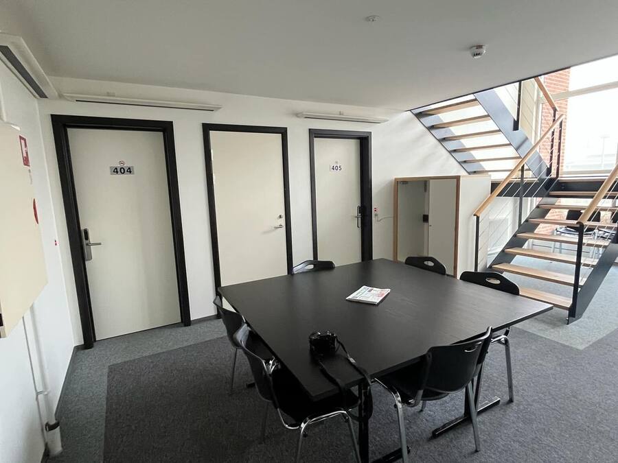 A conference room with a large table, four doors, and a staircase leading to an upper level.