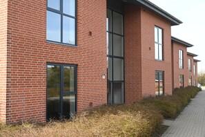 A modern brick building with large windows and a paved walkway. - Sport & Academy  (Farsø)