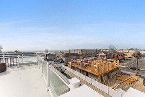 Una obra en construcción con estructura de madera, piscina y vistas al océano y edificios.