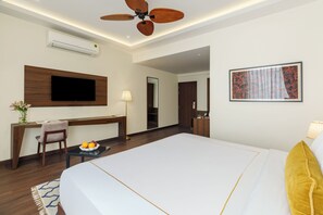Habitación de hotel con cama, escritorio, silla y televisor.