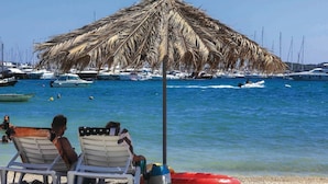 Two beach chairs under a thatched umbrella with a view of boats and yachts in the background. - Luxury Villa Malo (Seget)
