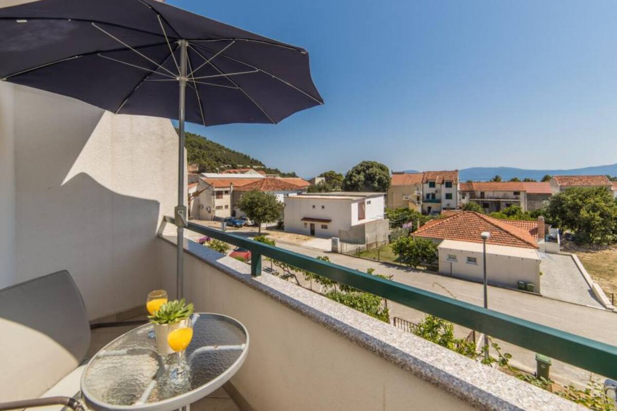 A balcony with a table, two chairs, and a black umbrella.