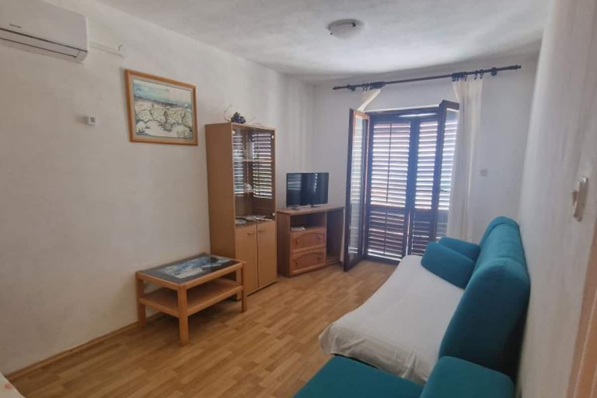 Una habitación con cama, televisor, armario y ventana con persianas.