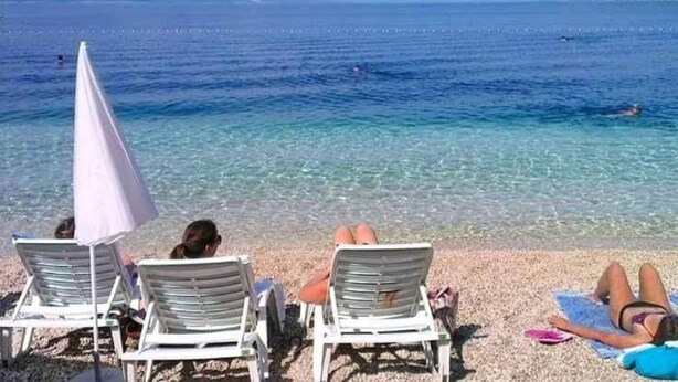 A beach with clear water, people sunbathing, and a distant mountain. - Peaceful Apartments With Style (Okrug)