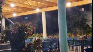 An outdoor patio area with wooden beams and hanging lights, surrounded by potted plants and outdoor furniture. - Peaceful Apartments With Style (Okrug)
