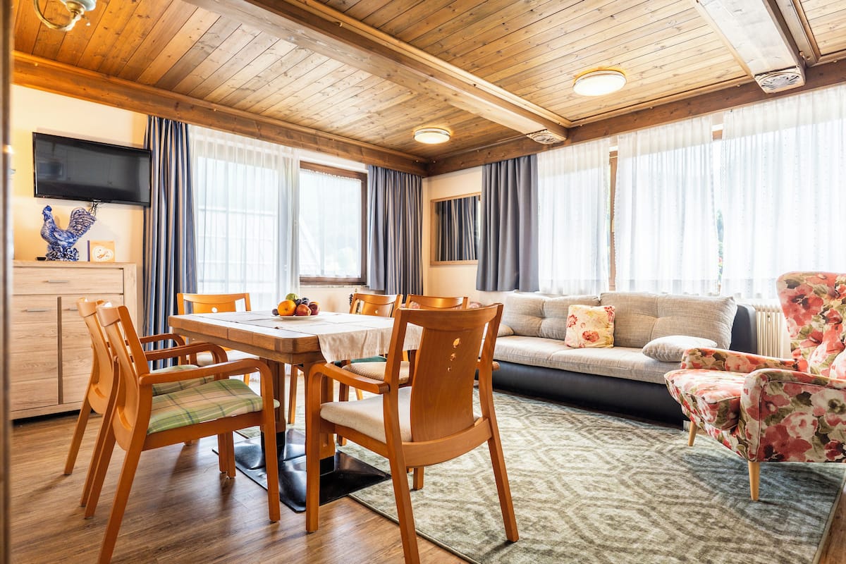A cozy living room with wooden furniture, a dining table, and a sofa.