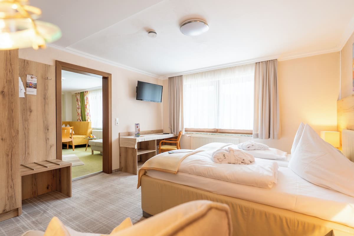 A hotel room with a bed, a desk, a chair, a television, and a window with curtains.