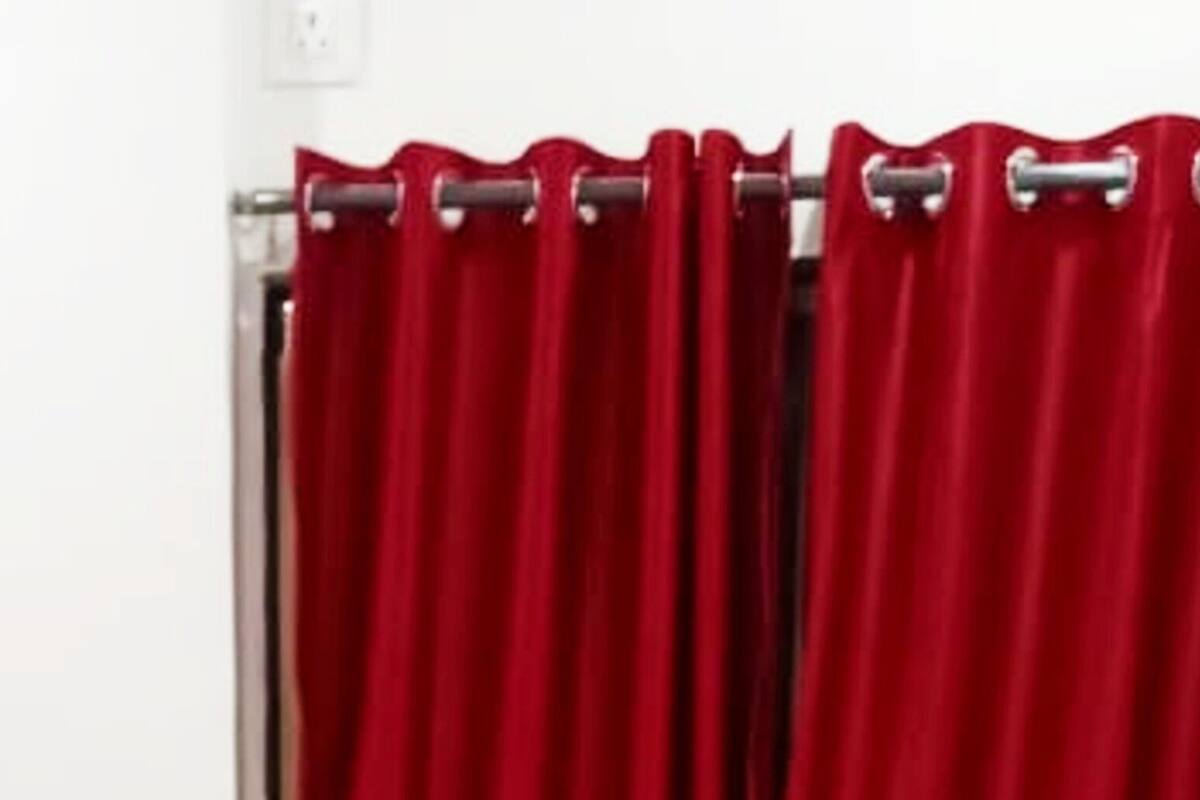 Una habitación de hotel con cama, cabecero de madera y cortinas rojas.